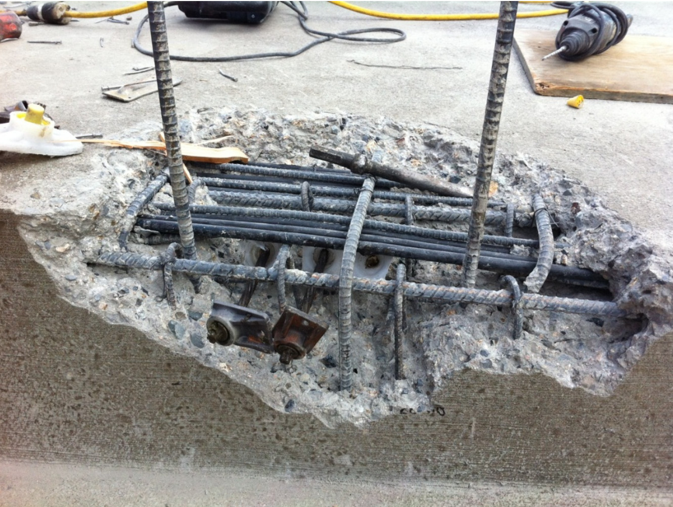 Serious concrete blowout and exposed rebar grid in the anchorage zone of a post-tension slab due to an internal void.